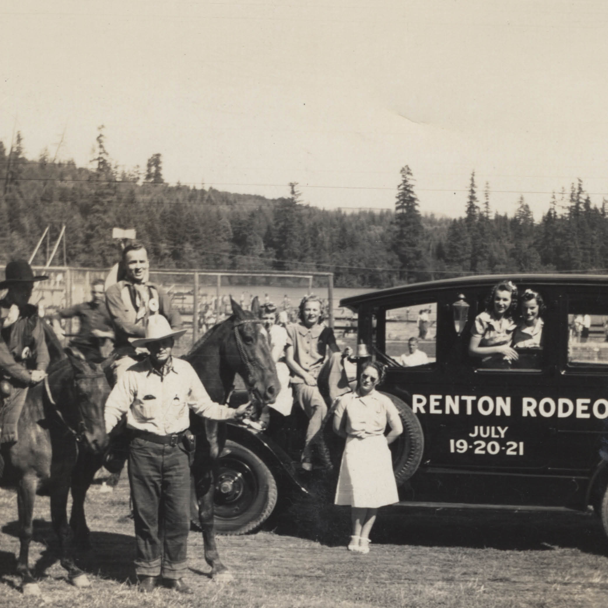 People and horses gathered around a Renton Rodeo car